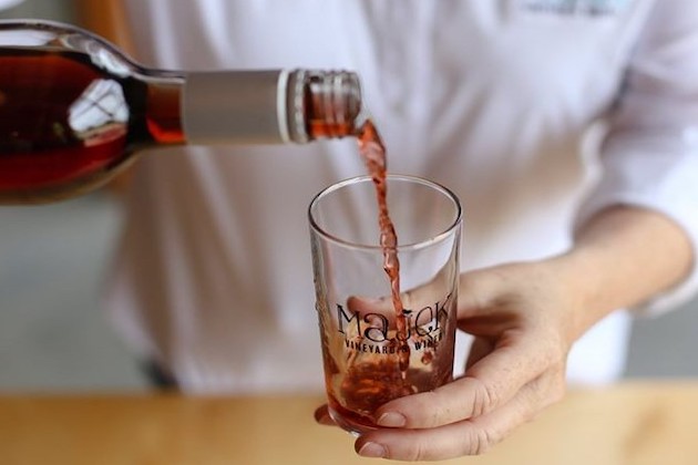 A woman's hand is pouring wine into a glass.