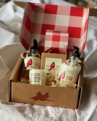 Mini bottle of lotion, hand and body wash, and a scented candle inside a cardboard box.